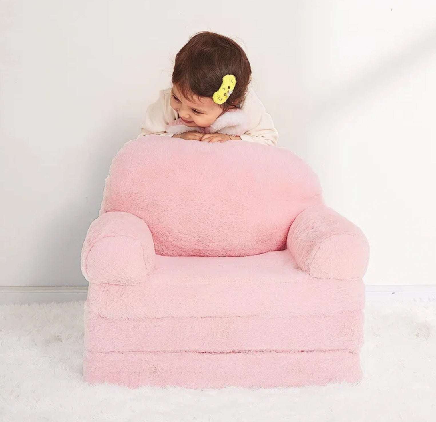 Pluizige roze kinder fauteuil met verlengstuk en zachte stof met kind erop leunend